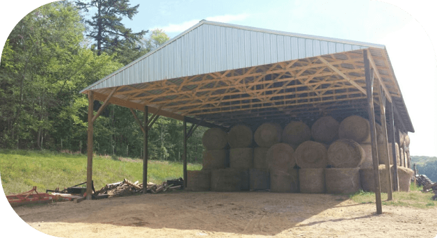 A run-in shelter stacked with round hay bales